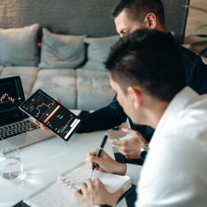 Two Men Discussing Graphs on Computer Screens