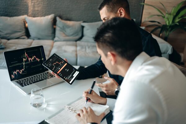 Two Men Discussing Graphs on Computer Screens